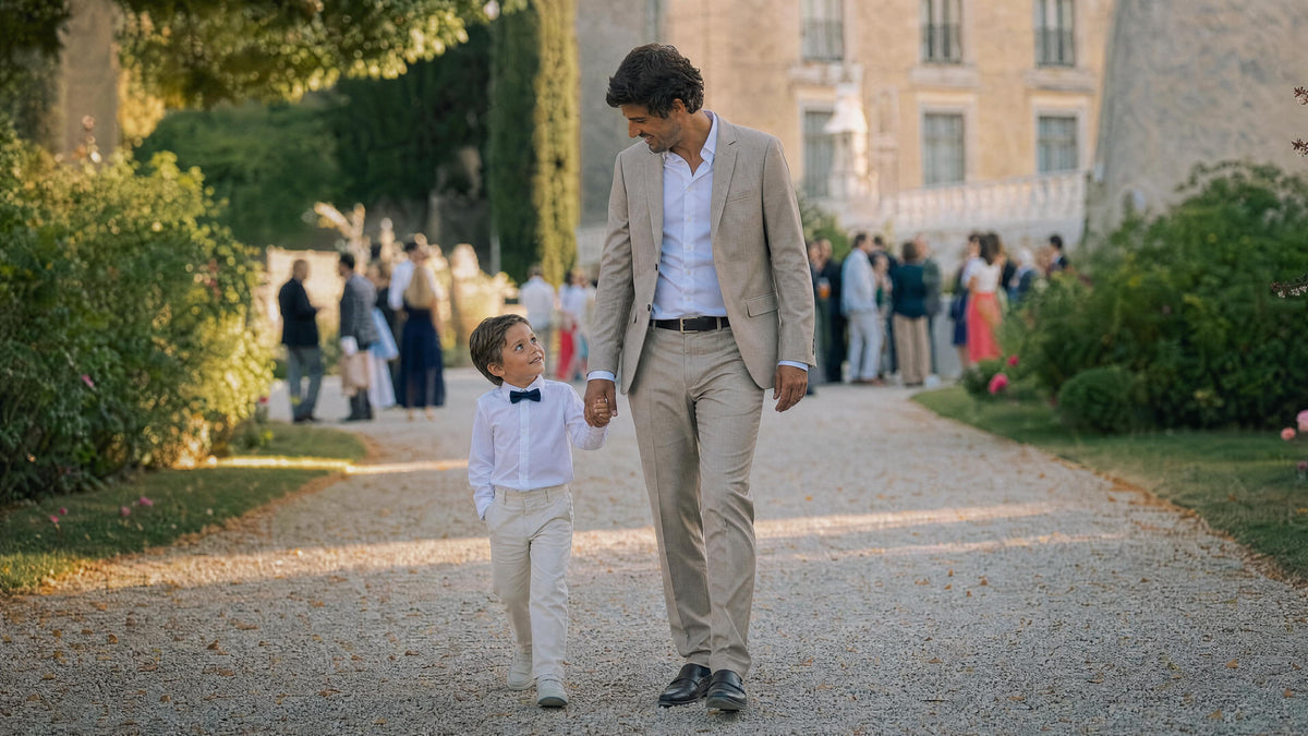 Enfant habillé pour un mariage marchant avec un adulte, tenue élégante et confortable. Afbeelding