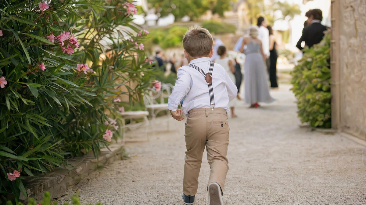 Enfant portant des bretelles pour une cérémonie, tenue élégante et naturelle. Afbeelding